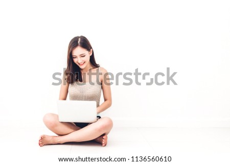 Beautiful woman sitting relax on floor working and typing technology of laptop computer against copy space for adding text with white wall background.Communication concept