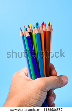  Hands holding a bunch of pencils on a blue background
