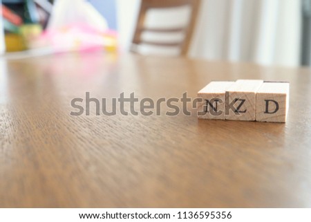 NZD (New Zealand Dollar) Text Block on Wooden Table