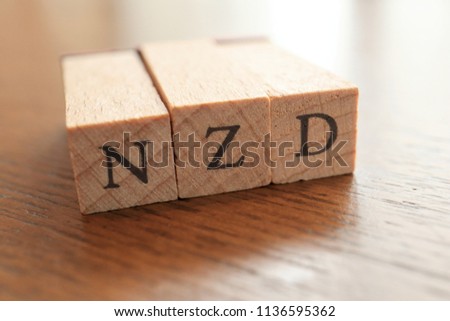 NZD (New Zealand Dollar) Text Block on Wooden Table