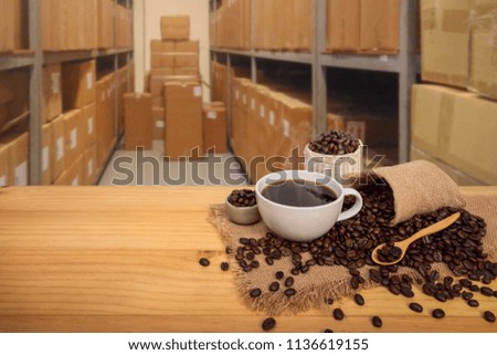 Hot cup of coffee with coffee beans on burlap sack, in warehouse background, with copy space