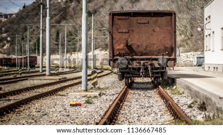 Industrial panorama view of the back of a brown vagon covered with rust. Vagon standing on rails.