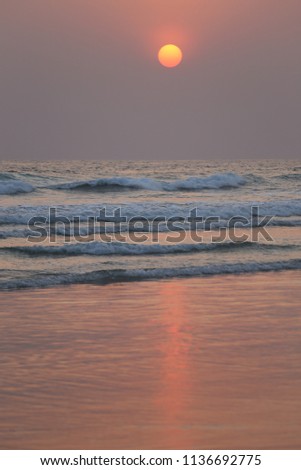 Colorful sunset on the atlantic ocean. Picture taken at assinie beach, ivory coast, africa. Seascape with pastel colors. White waves and orange reflects on the wet sand. Calm and quiet ambiance.