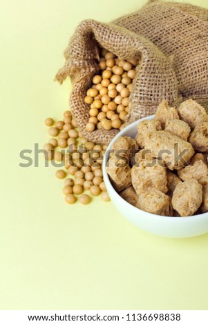 Organic soy products on light yellow background: soy beans, tofu and soy meat