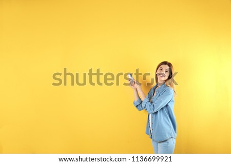 Woman with air conditioner remote on color background