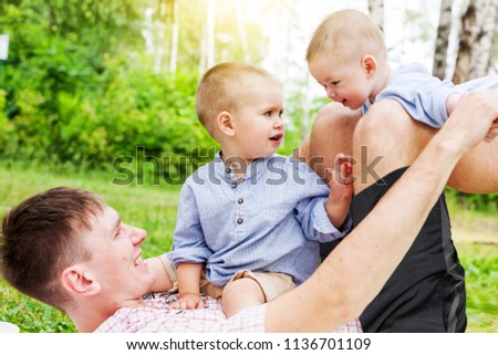 Young father with two small children sons having fun in the forest at a picnic in a beautiful sunny summer's day, father's day, love, family, and time together