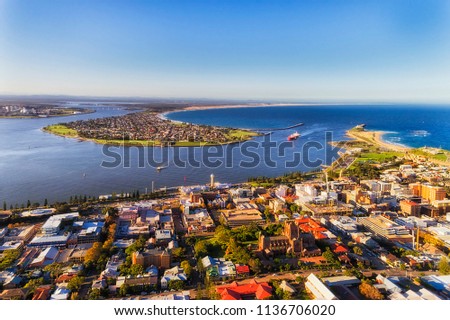 Delta of Hunter river at Newcastle city CBD behind Nobbys head via developed industrial and residential waterfront in aerial elevated view. Royalty-Free Stock Photo #1136706020
