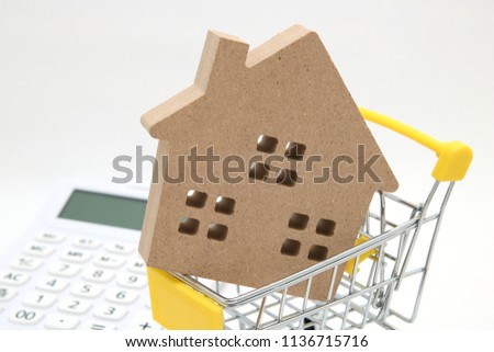 Miniature house, shopping cart and  calculator on white background.
Concept of buying new house, real estate and home mortgage.