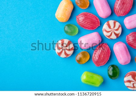 Many multicolored delicious caramel candies on a blue background