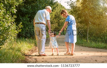 Back view of grandparents and baby grandchild walking on a nature path Royalty-Free Stock Photo #1136723777