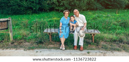 Grandparents and grandson posing for a photo sitting on a bench outdoors