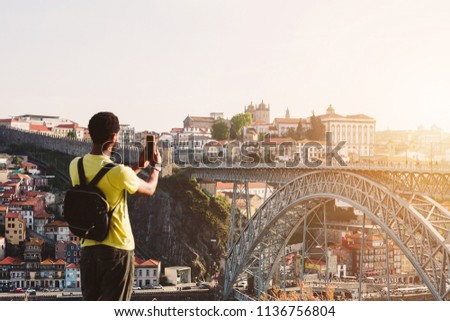 African man tourist take pictures on mobile phone of Ponte de Dom Luis I Bridge in Porto, Portugal