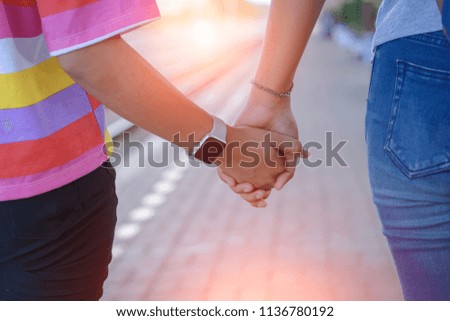 couple holding hands and walking together at train station