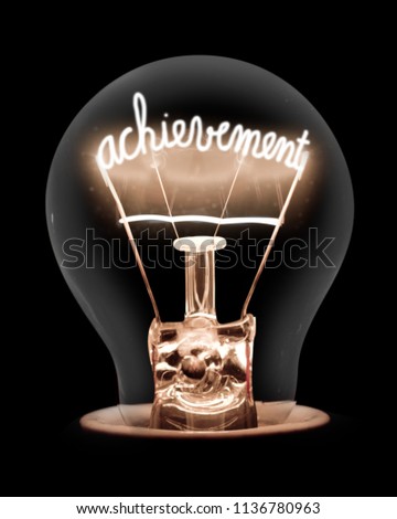 Photo of light bulb with shining fibre in ACHIEVEMENT shape on black background