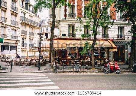 Cozy street with tables of cafe in quarter Montmartre in Paris, France. Architecture and landmarks of Paris. Postcard of Paris Royalty-Free Stock Photo #1136789414