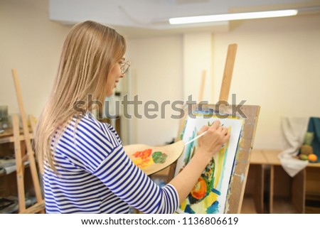 Young female artist painting still life in workshop