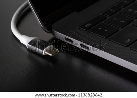 One USB type C cable disconnected from laptop computer on black background Royalty-Free Stock Photo #1136828642