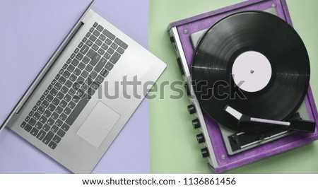 Laptop, vinyl player on a colored pastel background. Modern and outdated technology, top view
