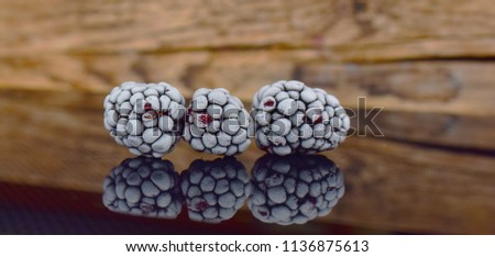 ripe blackberries covered with frost on the background of a wooden Board