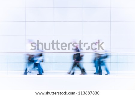 Many unrecognizable business people in a fair hall, intentional motion blur, blue tinted high resolution stock photo