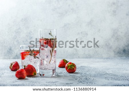 Alcoholic or non-alcoholic cocktail with strawberries and rosemary and ice in glass glasses. Free space for text.