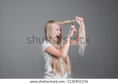 Attractive chaild girl  is cutting her long blond natural hair