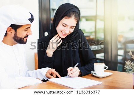 Arab man giving documents to sign to a woman in hijab