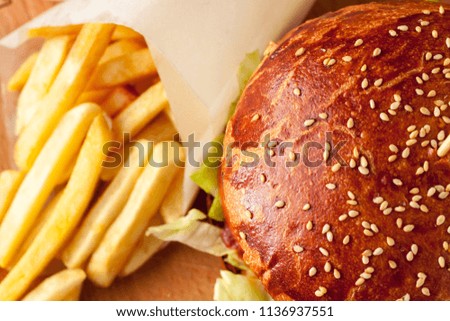 Craft beef burger and french fries on wooden cutting board
