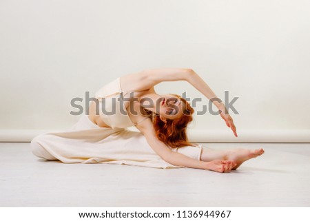 Young redhead woman dancing contemporary dance, posing in studio, sitting on floor. Copy space