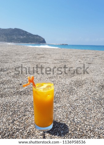 A glass of fresh orange juice on the beach sand