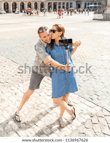 Selfie couple taking pictures Plaza Major in the old town of the capital of spain, Madrid Spain. Tourists people taking travel photos with smart phone on summer holidays.