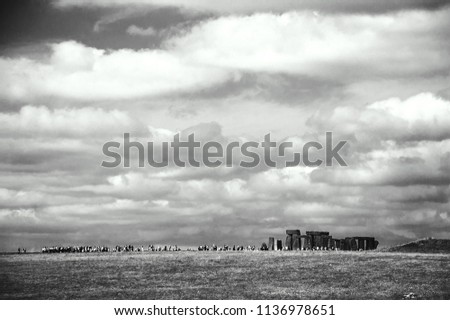 Stonehenge an ancient prehistoric monument in Wiltshire near Salisbury, England, UK. Long line of visitors. Black and white photo.