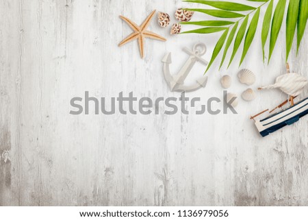 Palm leaves, seashells, boat, starfish anchor and other decoration on white wooden desk with empty space. Flat lay