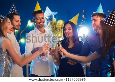 Young people with glasses of champagne at birthday party in club