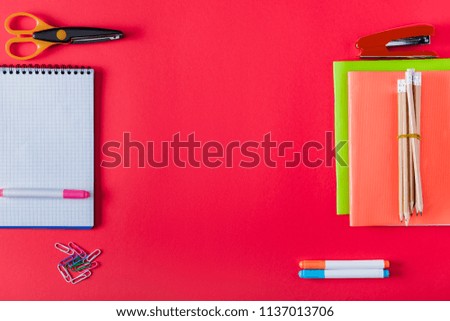 top view of arranged textbooks, stapler, markers, paper clips, scissors and blank notebook on red background 