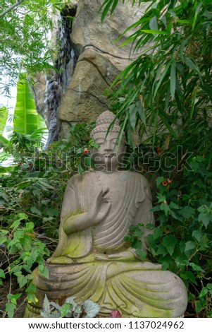Buddha in garden by waterfall