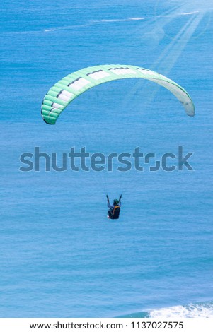 Paraglider tandem flying over the sea with blue water and mountains in bright sunny day, Summer Holiday