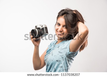 Pretty Indian/asian girl with Retro Camera, standing isolated over white background. holding or clicking pictures
