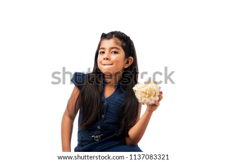 Cute little Indian/asian girl eating popcorn, isolated over white background
