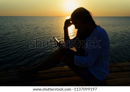 Girl in headphones on a bridge by the sea 