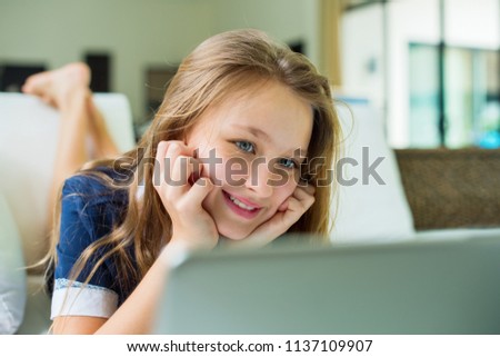 Pretty teenager looking in computer lying on sofa Concept free schooling education Homeschooling