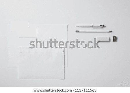 top view of various paper objects and office supplies on white surface for mockup