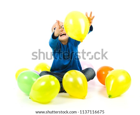 Happy young boy playing with balloons against a white background