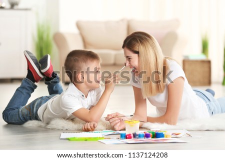 Mother with cute boy painting, indoors