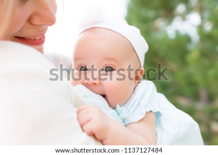Close up portrait of cut toddler in loving embrace of a young mother over nature in warm sunlight beams. Healthy family concept. Parental protection and care of baby. Sweet heart child, childhood