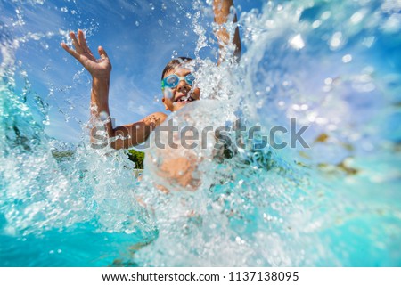 Happy boy playing and splashing in swimming pool
