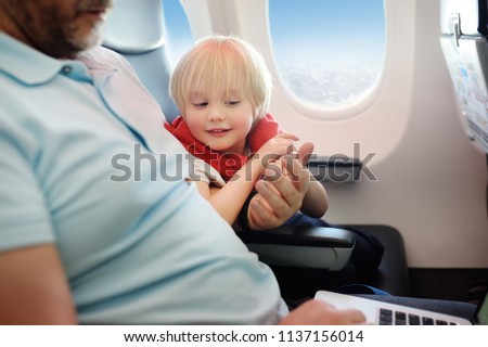 Portrait of little boy with his father during traveling by an airplane. Traveling with kids. Family enjoying trip in aircraft. Transportation safety
