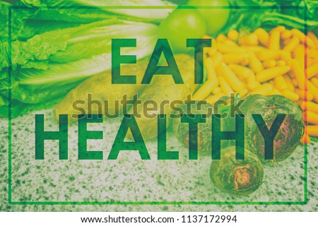 "EAT HEALTHY" diet motivational message written in big letters over real picture of vegetables, green design for poster or sign about weight loss motivation. Inspirational quote.