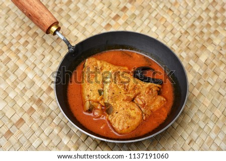 Top view of hot and spicy popular Kerala King or Barracuda fish curry made with coconut milk in earthen ware,clay or  mud pot . South Indian dish rice and fish is a favorite of tourists in Kochi.