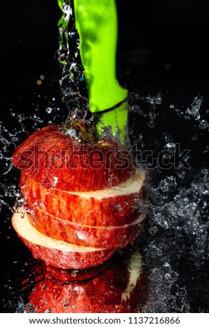 Gorgeous red apple sliced with green knife and drenched in fresh water background
